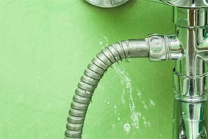Leaking water pipe connection with visible water spray, illustrating potential plumbing issues related to appliance water leaks and the need for professional repair services.