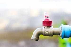 Outdoor faucet with red handle and blue hose, illustrating potential plumbing issues and outdoor water source inspections.