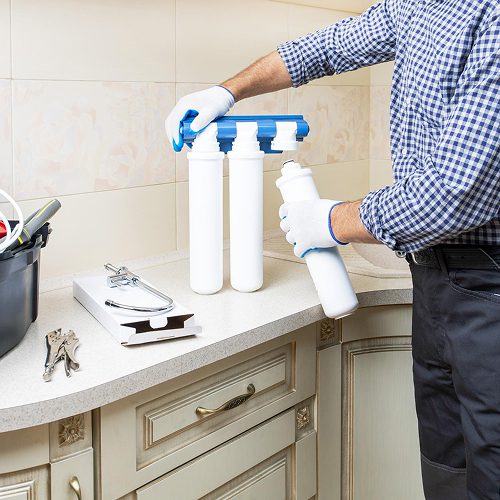 water softener system installation under a bathroom sink to help reduce signs of hard water and mineral buildup